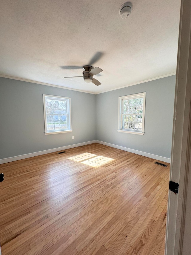 spare room featuring crown molding, light hardwood / wood-style floors, ceiling fan, and a wealth of natural light