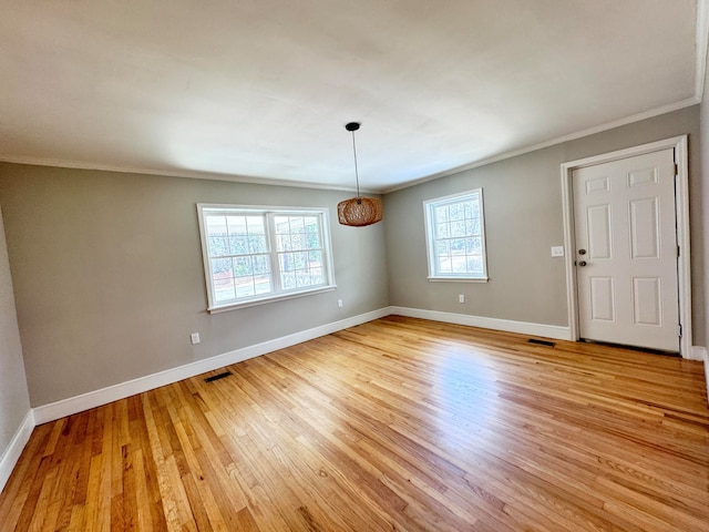 spare room featuring ornamental molding and light hardwood / wood-style floors