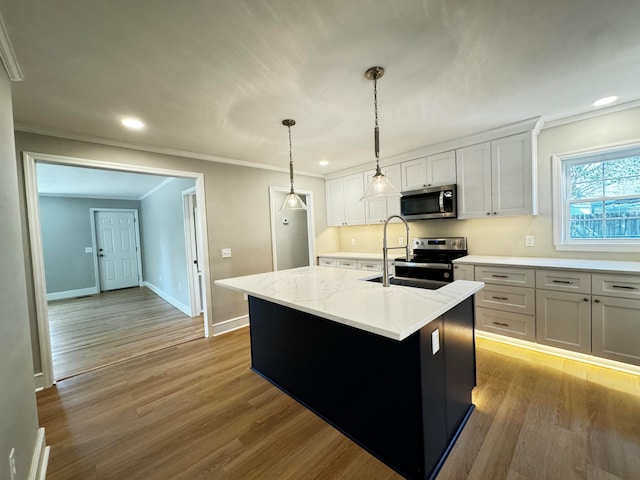 kitchen featuring light hardwood / wood-style floors, white cabinets, a center island with sink, stainless steel appliances, and hanging light fixtures