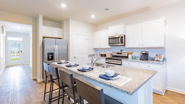 326 Watersglen Dr, Summerville, SC 29486 - kitchen with stainless steel appliances, a sink, light wood-type flooring, a center island with sink, and white cabinetry