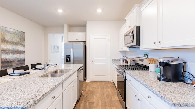 326 Watersglen Dr, Summerville, SC 29486 - kitchen featuring appliances with stainless steel finishes, a sink, light wood-style floors, white cabinetry, and light stone counters