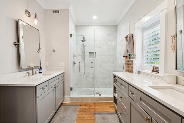 bathroom featuring vanity, hardwood / wood-style floors, ornamental molding, and a shower with door