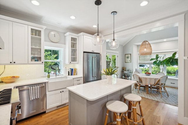 kitchen with white cabinetry, appliances with stainless steel finishes, sink, and decorative light fixtures