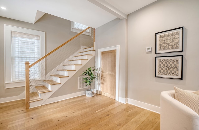 stairs with beam ceiling and hardwood / wood-style floors