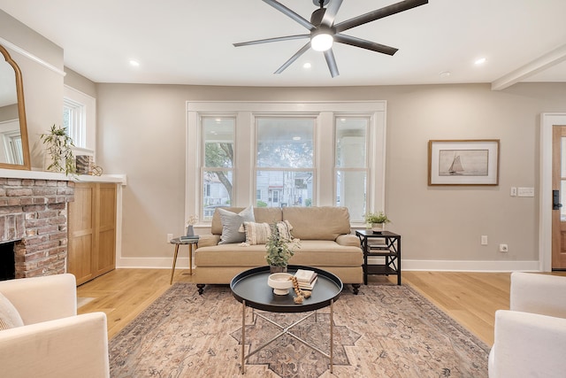 living room featuring ceiling fan, light wood-type flooring, and a fireplace