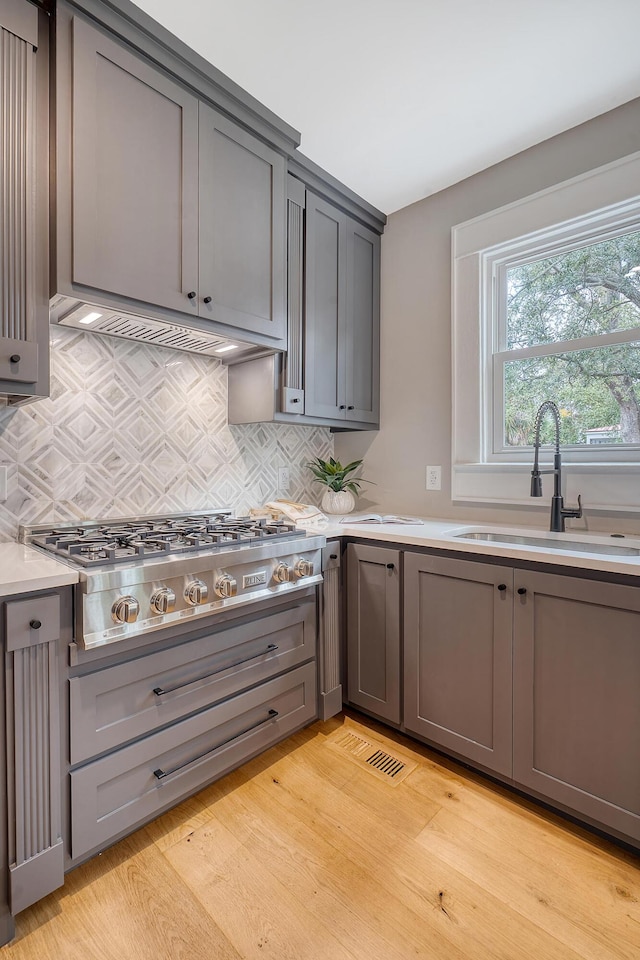 kitchen with gray cabinetry, sink, stainless steel gas cooktop, and light hardwood / wood-style flooring