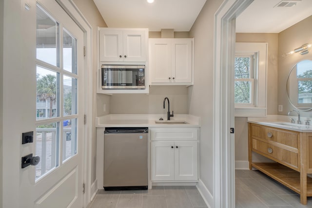 bar with white cabinets, sink, stainless steel appliances, and a wealth of natural light