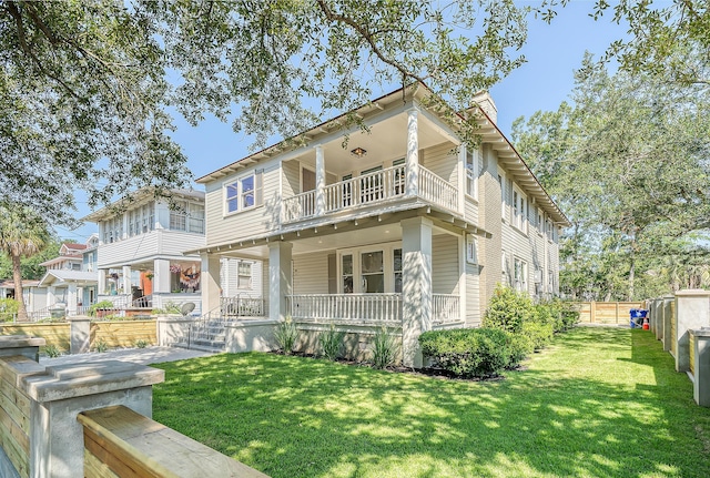 view of front facade with a porch, a balcony, and a front lawn