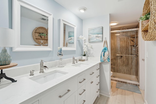 bathroom featuring vanity, wood-type flooring, a shower with shower door, and toilet