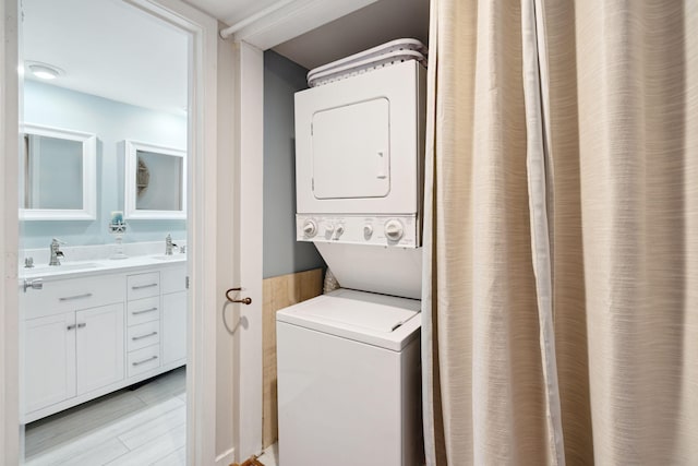 laundry room with light wood-type flooring, stacked washer / drying machine, and sink