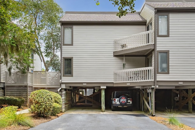 back of house featuring a balcony and a carport