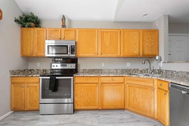 kitchen featuring light stone countertops, light hardwood / wood-style floors, sink, and stainless steel appliances