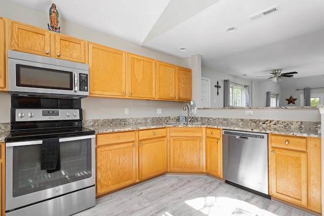 kitchen featuring light wood-type flooring, ceiling fan, appliances with stainless steel finishes, and plenty of natural light