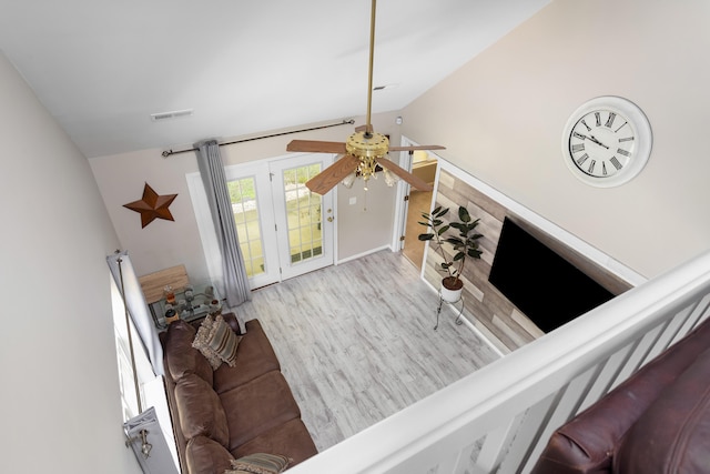 living room featuring light hardwood / wood-style floors, vaulted ceiling, and ceiling fan