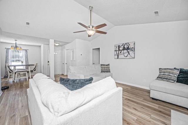 living room with a textured ceiling, lofted ceiling, ceiling fan with notable chandelier, and hardwood / wood-style flooring