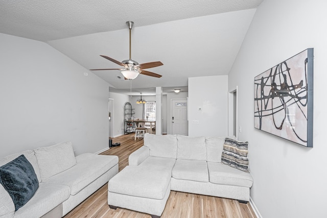 living room featuring ceiling fan, vaulted ceiling, a textured ceiling, and light hardwood / wood-style flooring