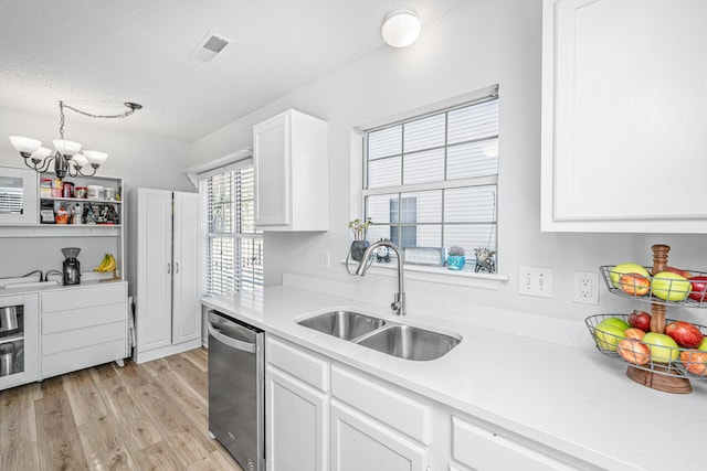 kitchen featuring a notable chandelier, a textured ceiling, stainless steel dishwasher, white cabinets, and sink