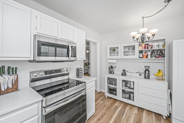 kitchen featuring white cabinetry, stainless steel appliances, a notable chandelier, and hanging light fixtures