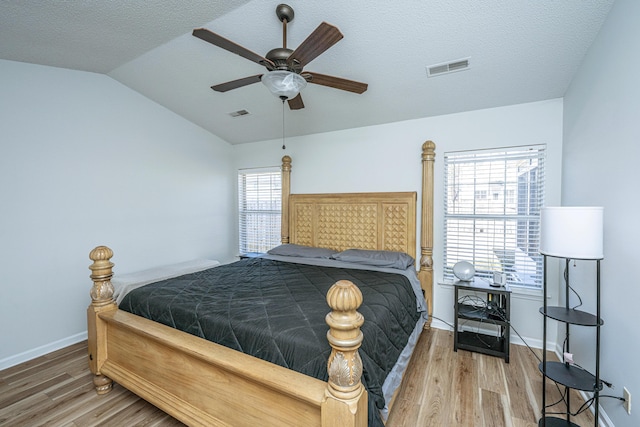 bedroom with hardwood / wood-style floors, ceiling fan, lofted ceiling, a textured ceiling, and multiple windows