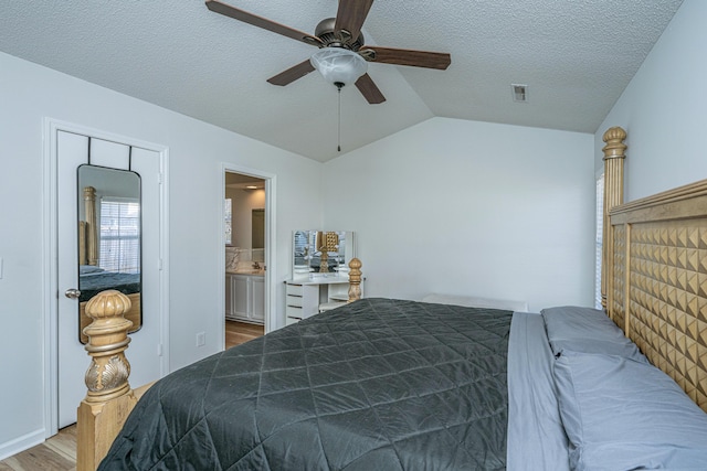 bedroom featuring a textured ceiling, connected bathroom, vaulted ceiling, ceiling fan, and light hardwood / wood-style flooring