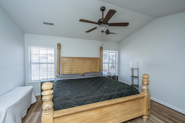 bedroom featuring ceiling fan, vaulted ceiling, dark hardwood / wood-style flooring, and multiple windows