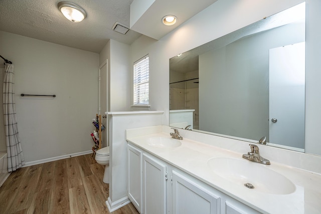 bathroom featuring toilet, a textured ceiling, wood-type flooring, and vanity