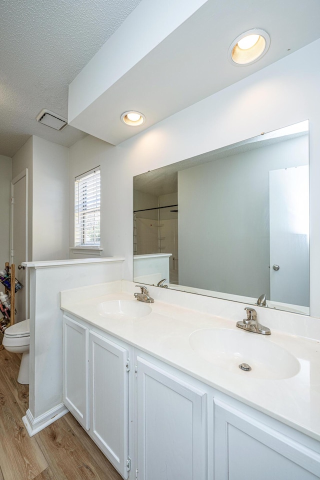 bathroom with toilet, vanity, walk in shower, hardwood / wood-style floors, and a textured ceiling