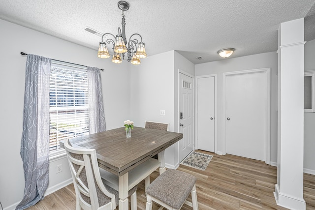 dining room featuring a textured ceiling, an inviting chandelier, and light hardwood / wood-style flooring