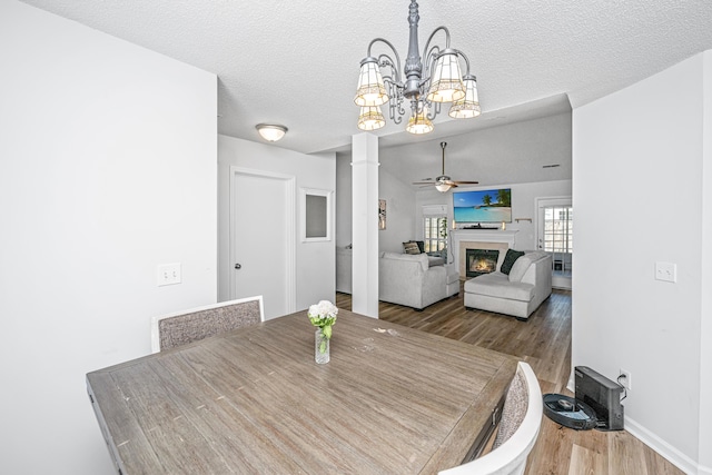 dining room with ceiling fan with notable chandelier, a textured ceiling, and wood-type flooring