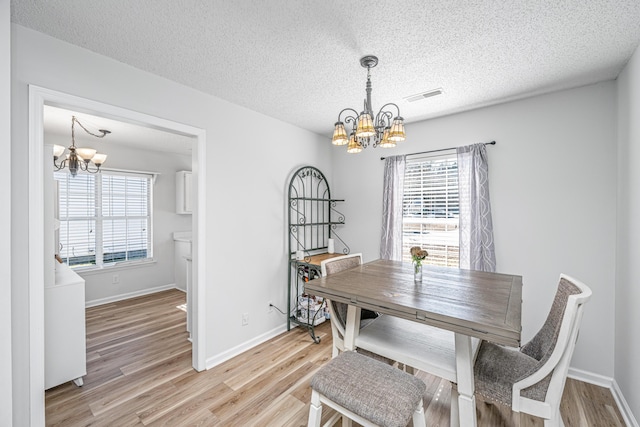 dining room featuring a wealth of natural light, a textured ceiling, and an inviting chandelier