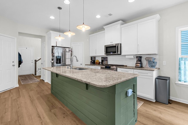 3789 Tupelo Branch Row, Mount Pleasant, SC 29429 - kitchen featuring appliances with stainless steel finishes, light wood-style flooring, tasteful backsplash, white cabinets, and a kitchen island with sink