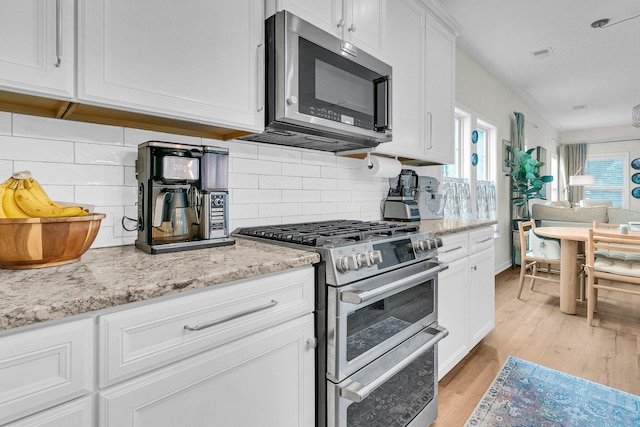 3789 Tupelo Branch Row, Mount Pleasant, SC 29429 - kitchen featuring appliances with stainless steel finishes, white cabinets, light wood finished floors, light stone countertops, and tasteful backsplash