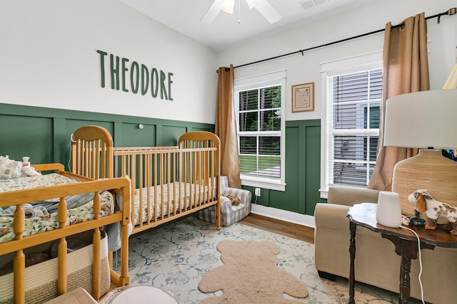 3789 Tupelo Branch Row, Mount Pleasant, SC 29429 - bedroom with a decorative wall, wood finished floors, a wainscoted wall, and a ceiling fan