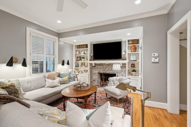 living room featuring ceiling fan, light wood-type flooring, a brick fireplace, and crown molding