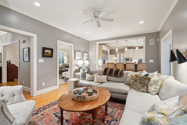 living room with ceiling fan, crown molding, and light hardwood / wood-style floors