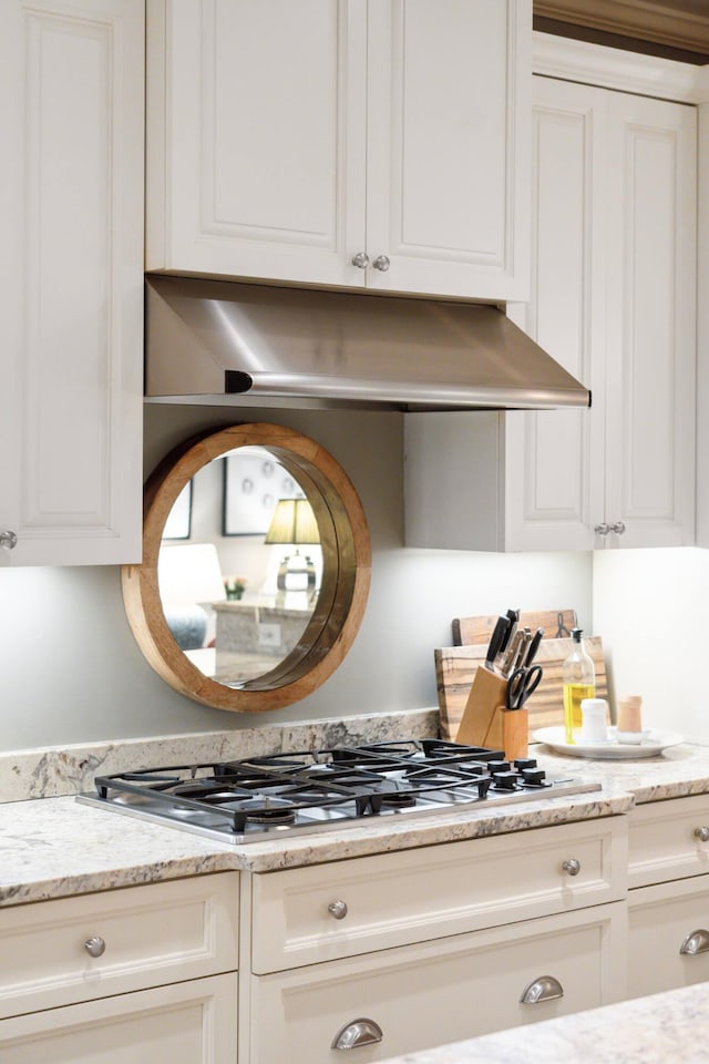 kitchen featuring light stone counters, stainless steel gas cooktop, and white cabinetry