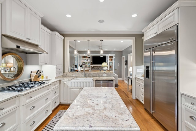 kitchen with decorative light fixtures, stainless steel appliances, light stone counters, and white cabinetry