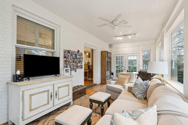 living room featuring ceiling fan, french doors, brick wall, and hardwood / wood-style flooring