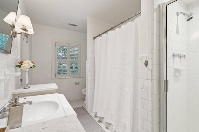 bathroom with tile walls, a shower with shower curtain, vanity, and toilet