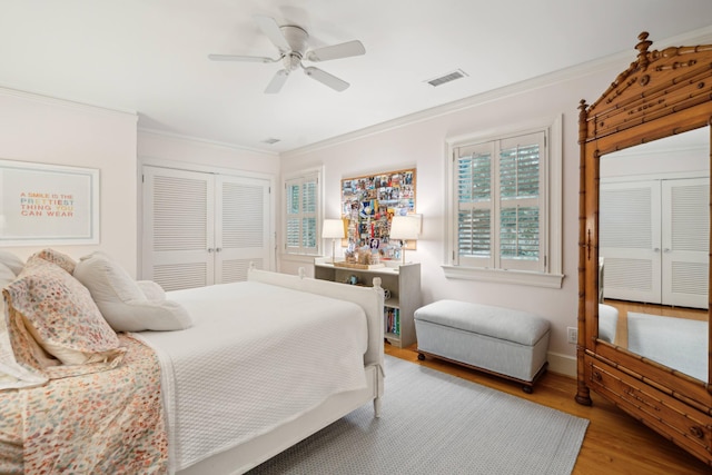 bedroom featuring ornamental molding, light wood-type flooring, ceiling fan, and a closet