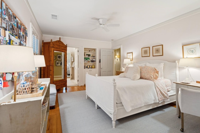 bedroom with wood-type flooring, ceiling fan, and crown molding