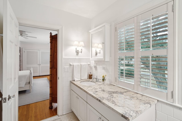 bathroom featuring vanity, tile walls, ceiling fan, and hardwood / wood-style flooring