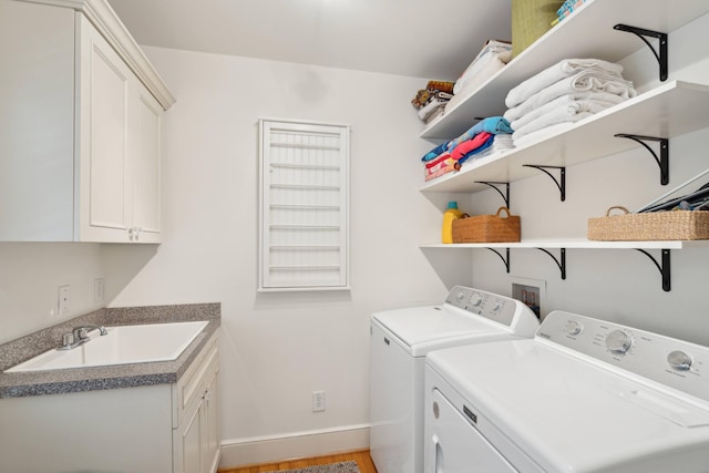 clothes washing area with cabinets, washing machine and clothes dryer, light hardwood / wood-style flooring, and sink