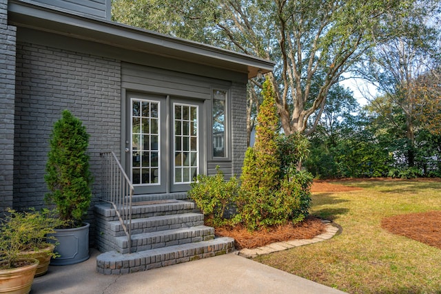 view of exterior entry featuring a lawn