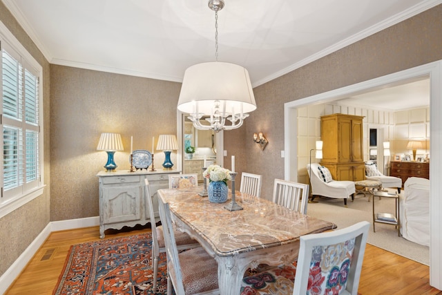 dining space featuring ornamental molding, a notable chandelier, and light hardwood / wood-style floors