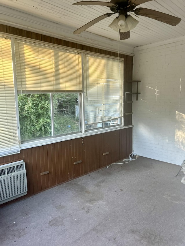 empty room with a wealth of natural light, light colored carpet, wooden walls, and brick wall