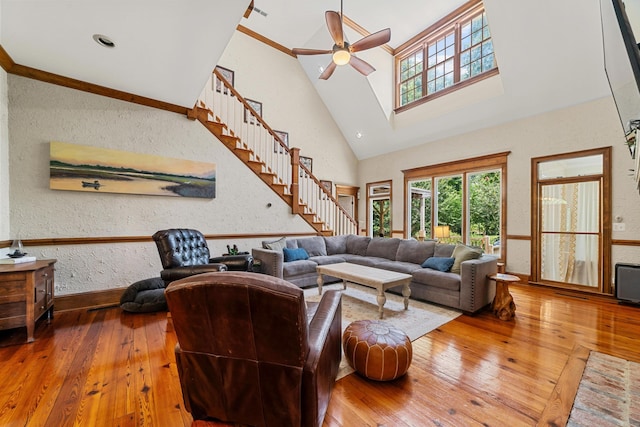 living room with ceiling fan, ornamental molding, hardwood / wood-style floors, and high vaulted ceiling