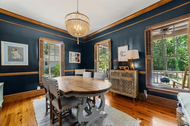 dining space featuring wood-type flooring, ornamental molding, and a notable chandelier