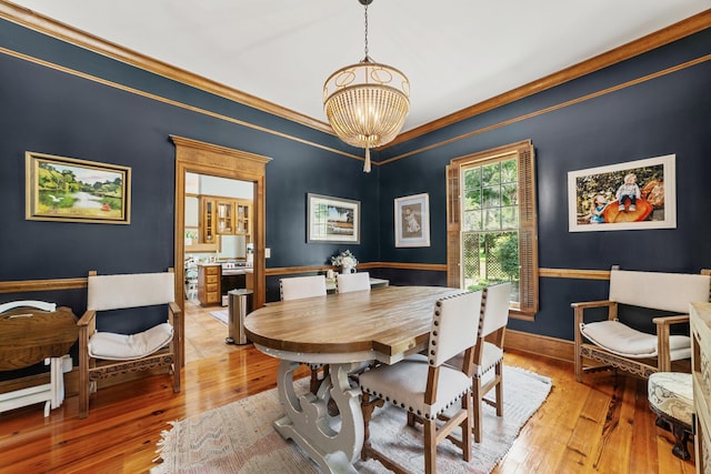 dining area with light hardwood / wood-style flooring, ornamental molding, and a chandelier