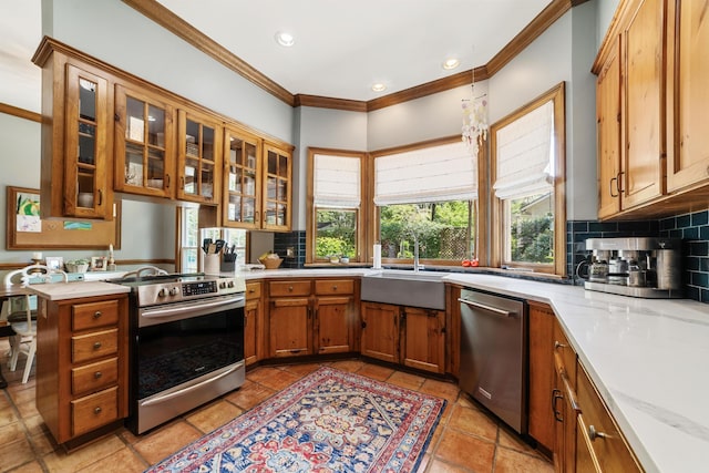 kitchen featuring light stone countertops, stainless steel appliances, tasteful backsplash, sink, and crown molding